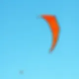 A vibrant duotone kite soaring against a clear blue sky
