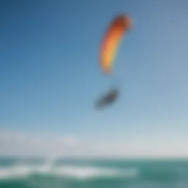 A kiteboarder performing tricks with a brightly colored kite against a blue sky