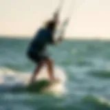 Kiteboarder riding a wave under clear skies